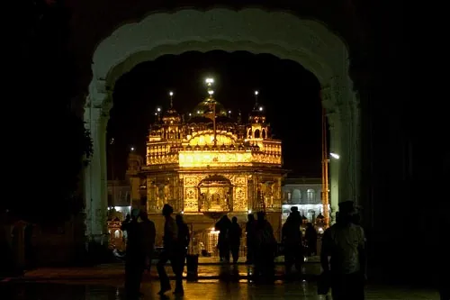 Nočný pohľad na  Zlatý chrám cez jednu zo vstupných brán. (Amritsar)